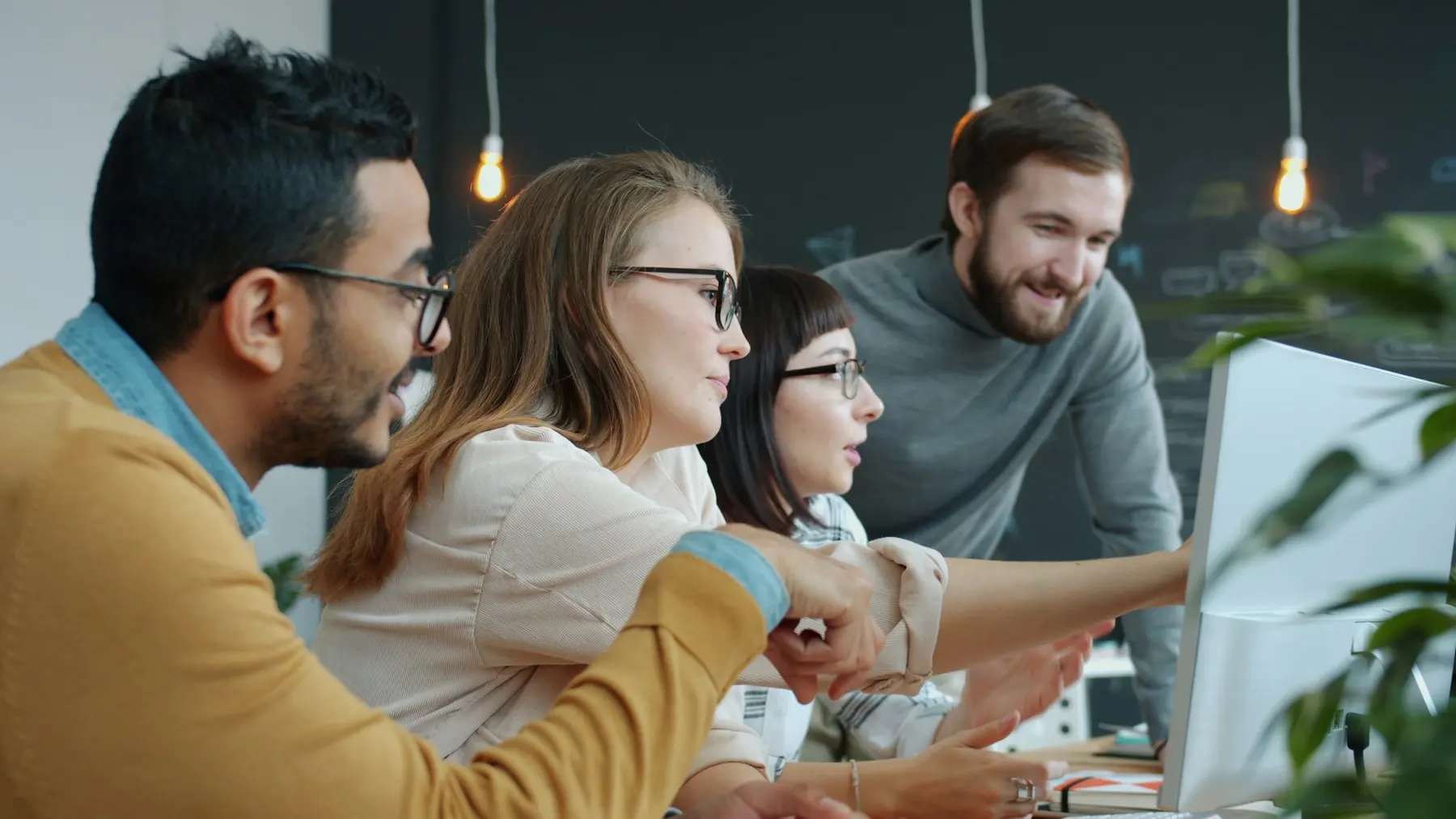 A team closing a deal with a handshake around a computer