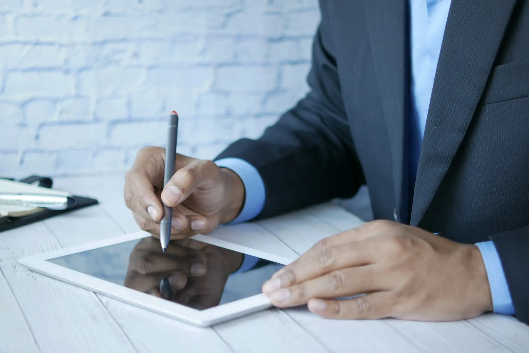 A person signing a document on a tablet with a stylus